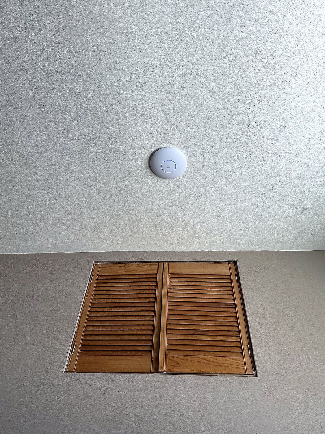 UniFi ceiling access point beside a louvred access hatch