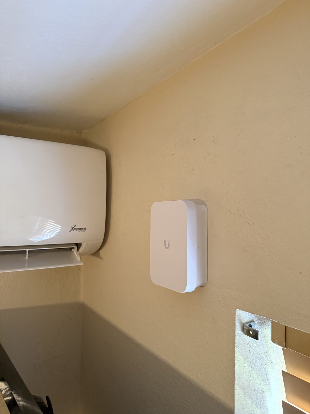 UniFi gateway wall-mounted in a utility corner - out of the way, always on