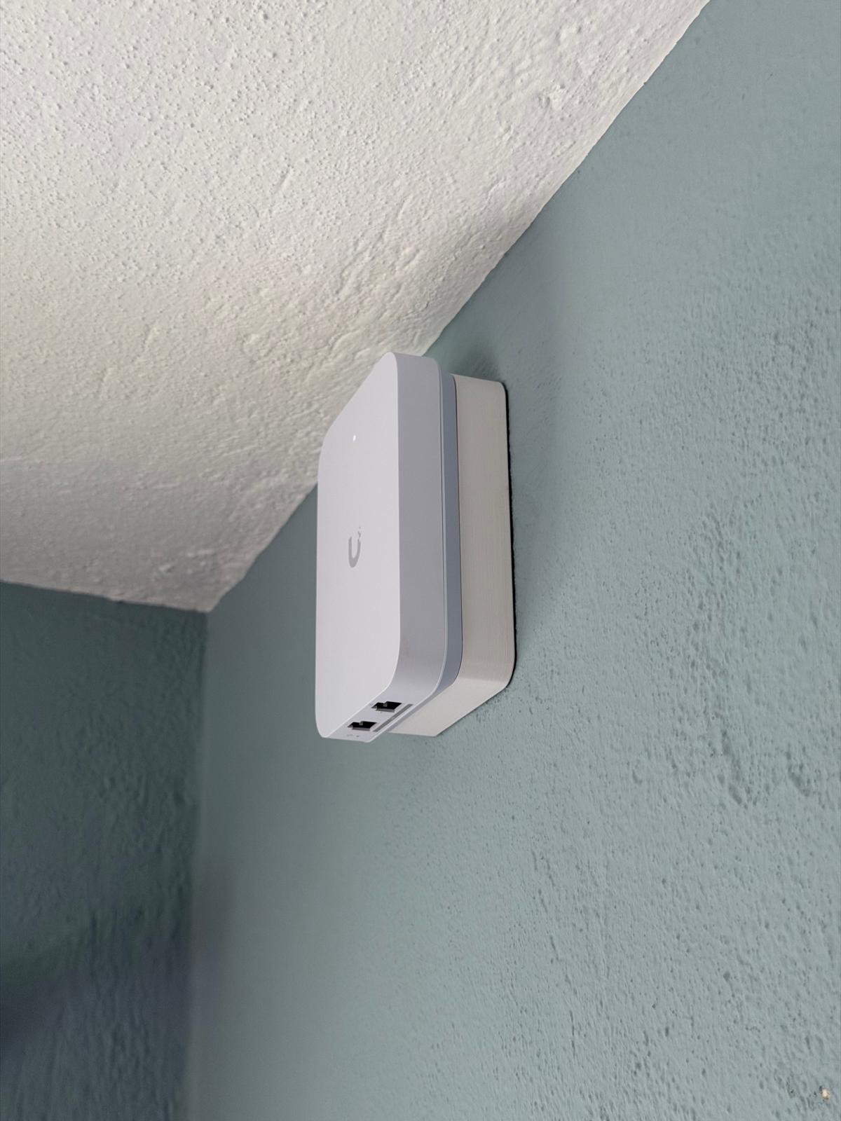 UniFi Express tucked high in the corner - out of sight, full signal