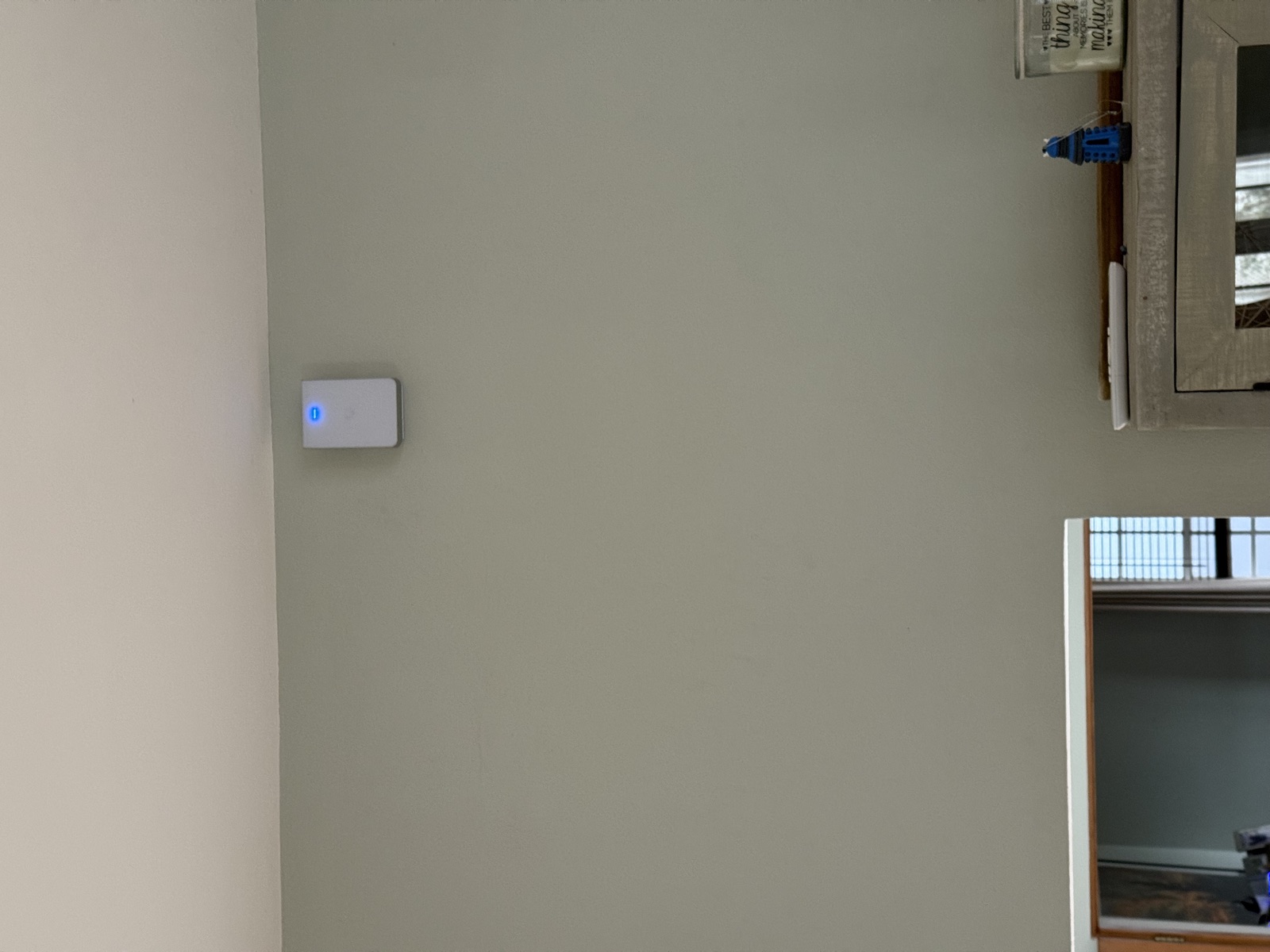 Wall access point up high on a sage-green wall - connected and glowing