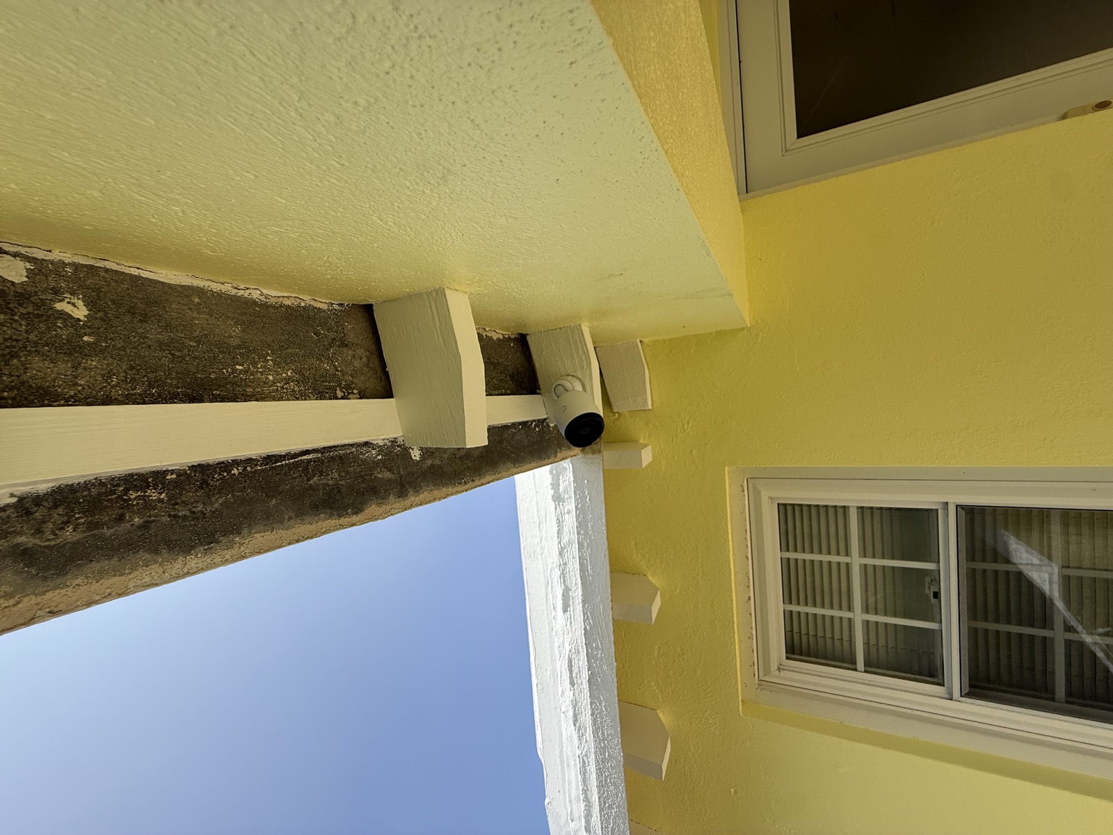 Bullet camera tucked at the eave of a yellow Bermuda home