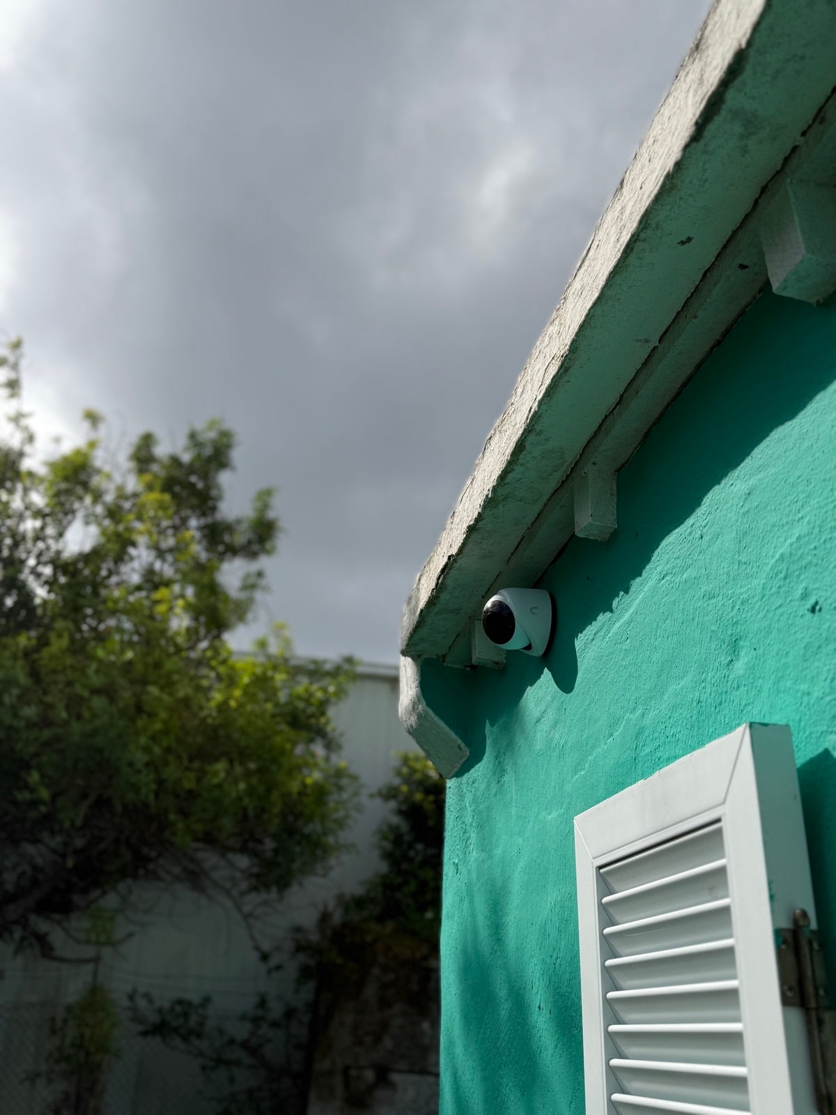 Dome camera under the eave of a teal-painted home