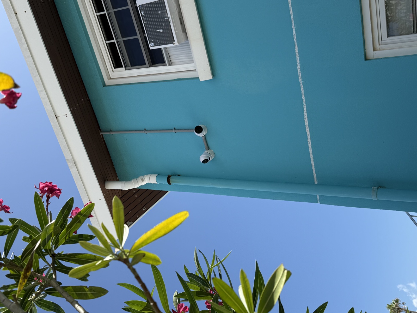 Turret and bullet pair covering two angles of a teal Bermuda home